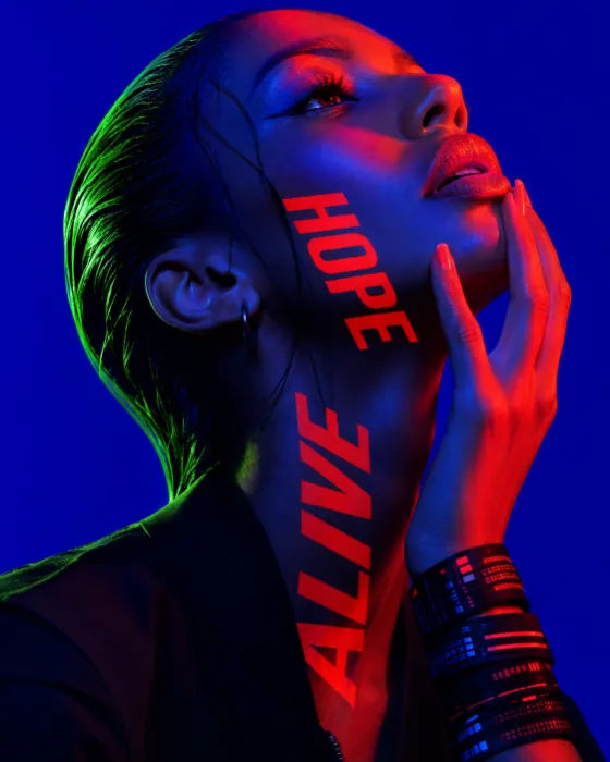 Experimental fashion close-up with an upward gaze, slick hair, neon color blocking and bold body-integrated typography.