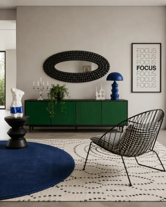 Eclectic contemporary lounge with emerald sideboard, cobalt blue accents, graphic rugs, black sculptural chair, mirror, and decor.