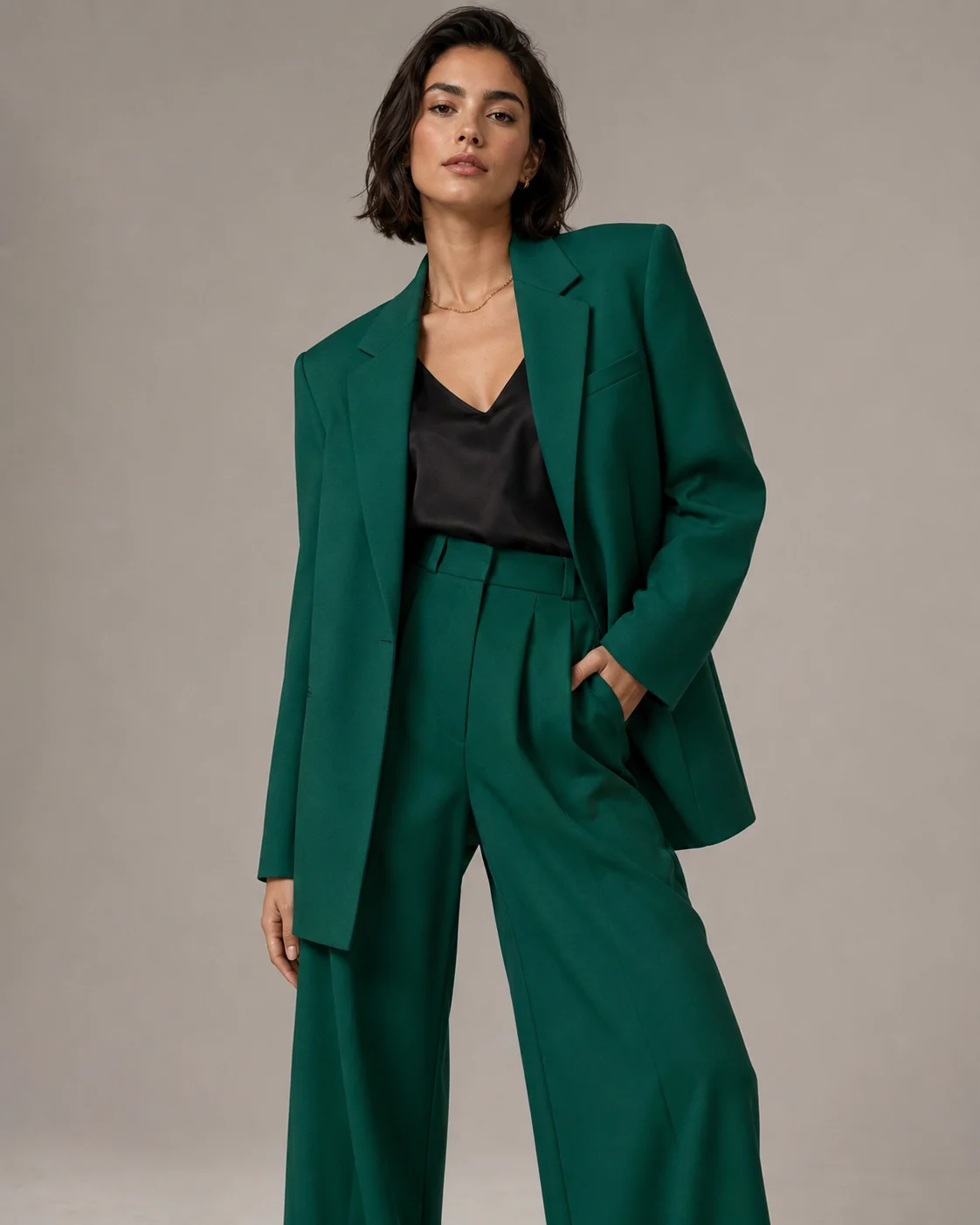 Adult woman in emerald green tailored blazer and wide-leg trousers, modern fashion.