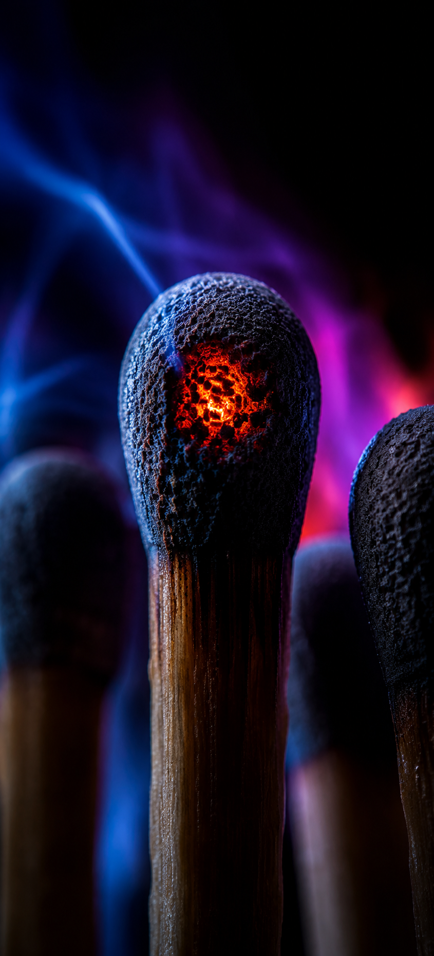 Macro phone wallpaper showing a glowing orange match head surrounded by blue and violet blurred light.