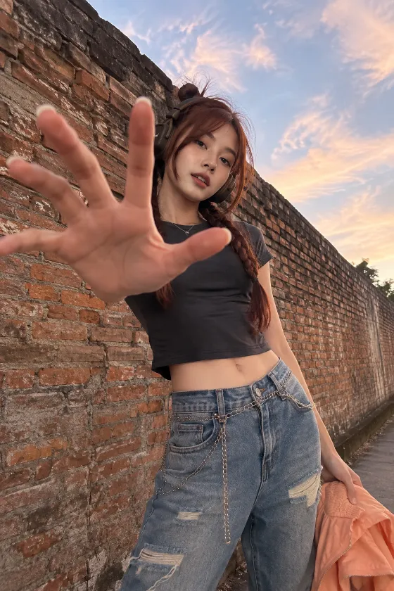 Casual headphone streetwear with distressed blue jeans, chain belt, and cropped charcoal top