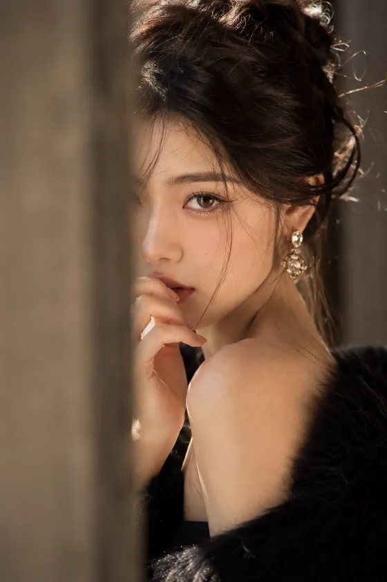Close-up editorial beauty portrait with warm natural light, black velvet texture, and elegant gold earrings.