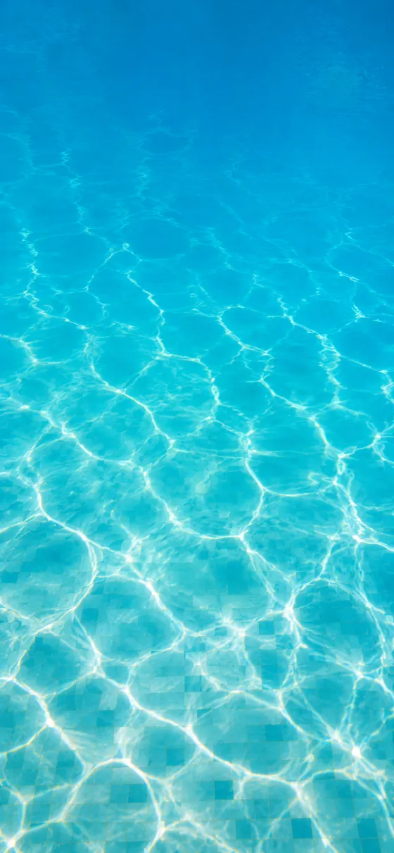 Top-down view of crystal-clear turquoise water with shimmering light patterns and subtle mosaic.