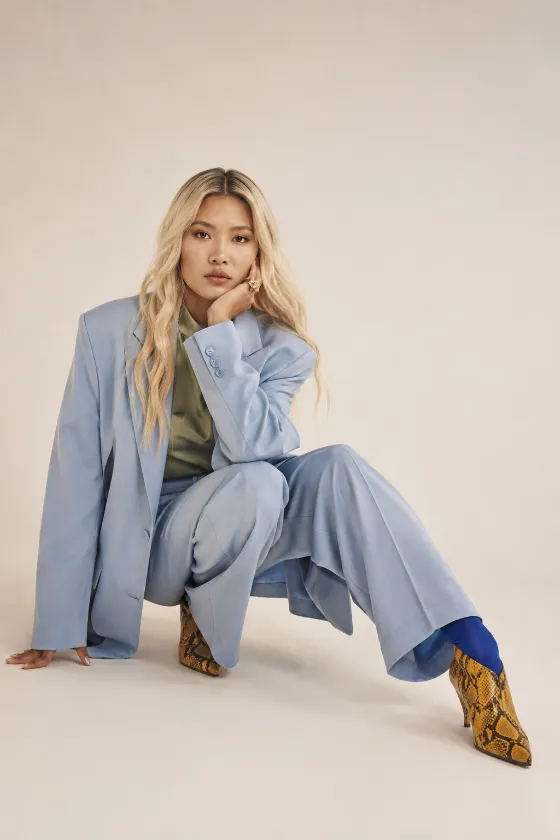 Editorial fashion portrait with oversized powder-blue suit and sculptural pose.