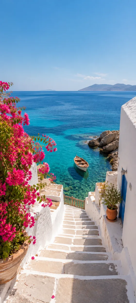 White seaside stairs with pink bougainvillea leading down to turquoise water and a small wooden boat.