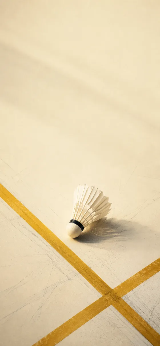 A minimalist feather shuttlecock resting on a cream badminton court with golden diagonal lines and soft shadows.