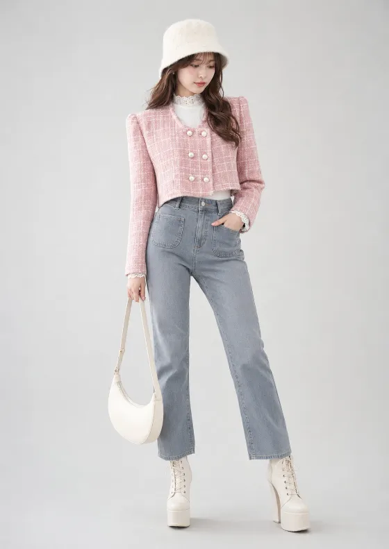Woman posing in a pale studio wearing a pink tweed jacket, gray jeans, fuzzy ivory hat, cream handbag and tall ivory lace-up platform boots.