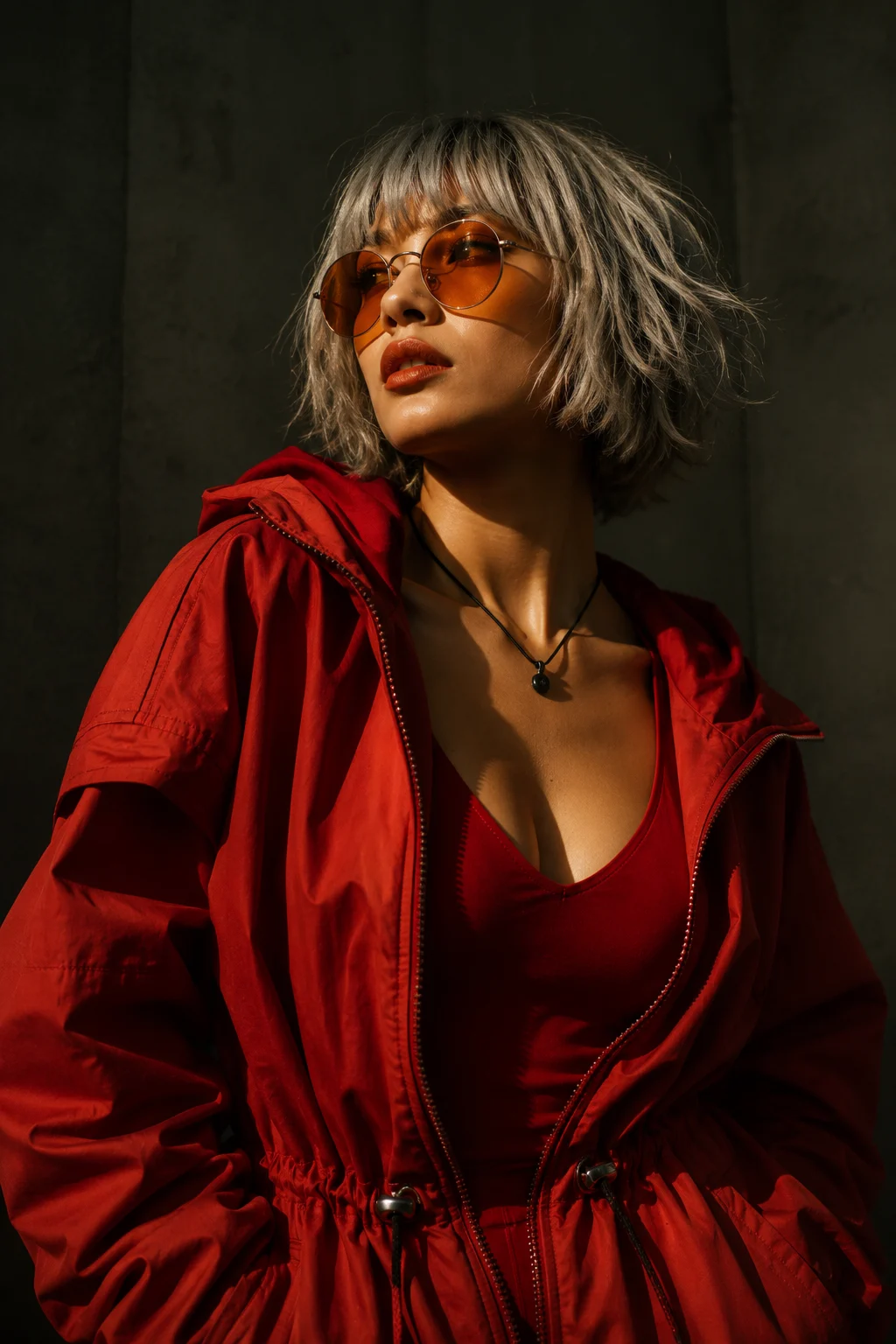 Red Y2K streetwear portrait with amber sunglasses, oversized hooded jacket, fitted red top, and short silver-gray bob hair.