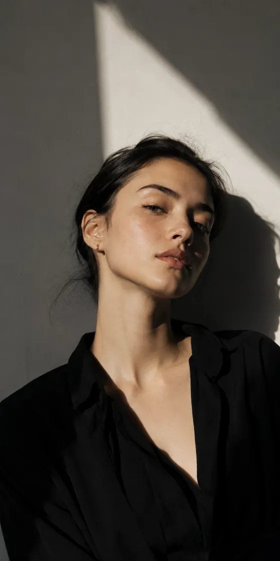 Woman in a vertical editorial portrait with sharp shadows, clean geometric forms, and muted studio tones.