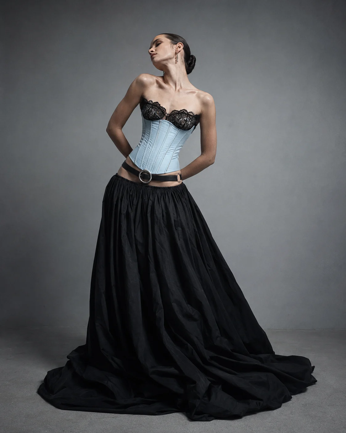 Studio fashion portrait with pale blue corset, black lace neckline, and full black skirt.