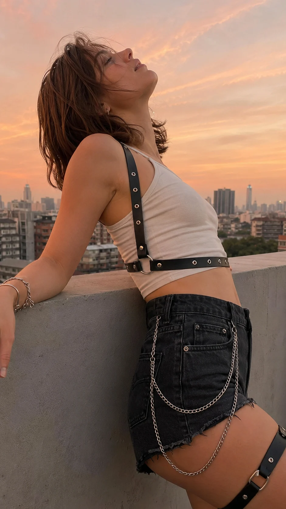 Woman looks over her shoulder at a waterfront railing at night, with city skyline lights behind her in a realistic low-light smartphone photo.