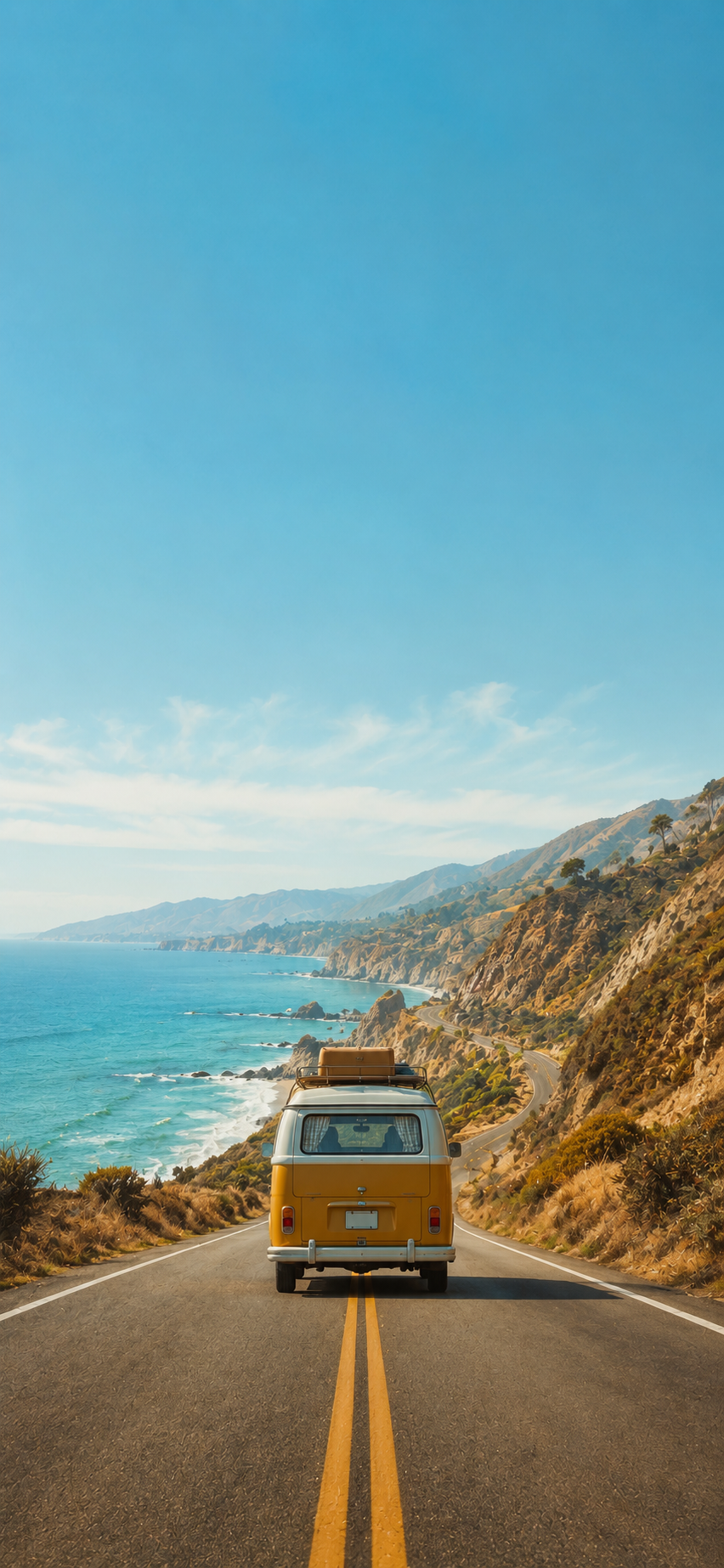 Vintage yellow camper van driving on a coastal highway beside a turquoise ocean under a clear blue sky.