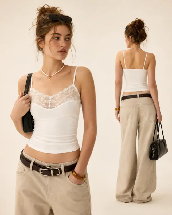Two studio views of one woman wearing a white lace camisole, low-rise beige wide-leg trousers, layered dark belts, pearl jewelry, sunglasses, and black bags.