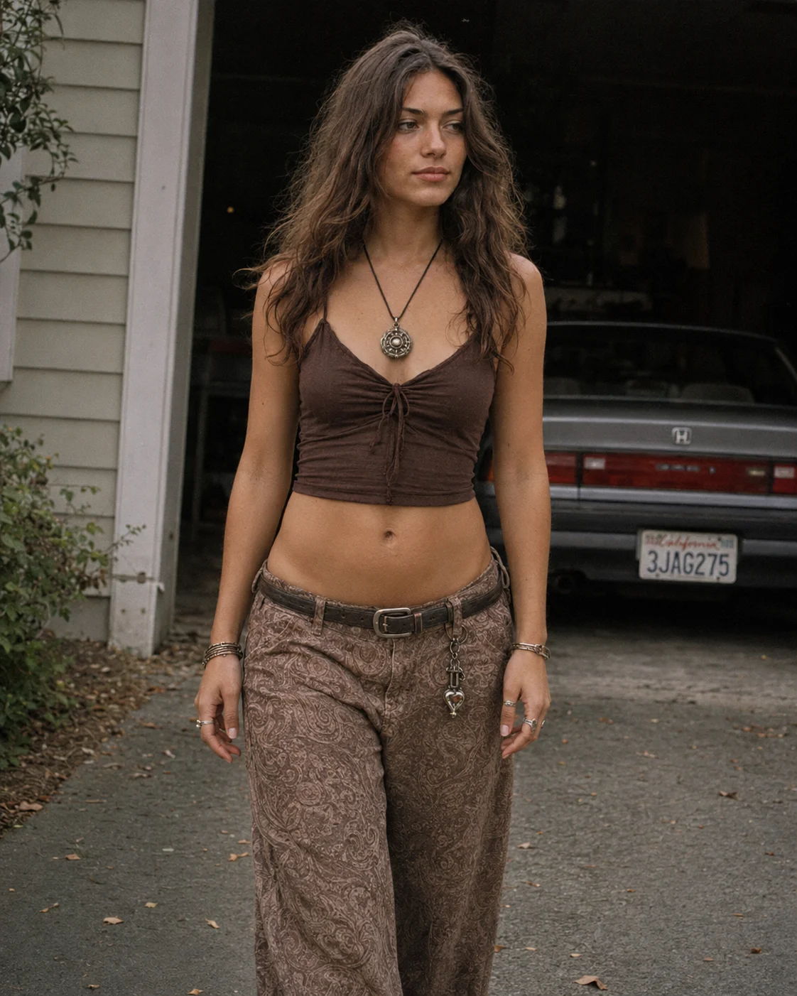 Y2K boho streetwear look with a brown cropped camisole, paisley wide-leg pants, pendant necklace, and relaxed street-style mood.