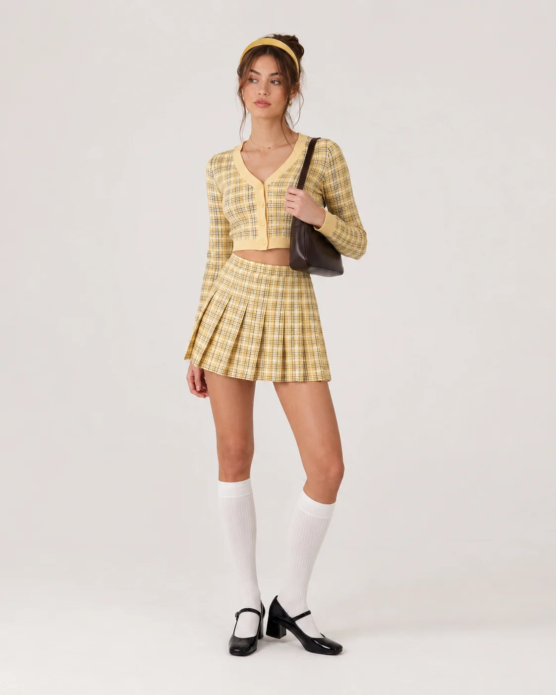 Young woman in a yellow plaid two-piece set, knee-high socks, and Mary Jane shoes.